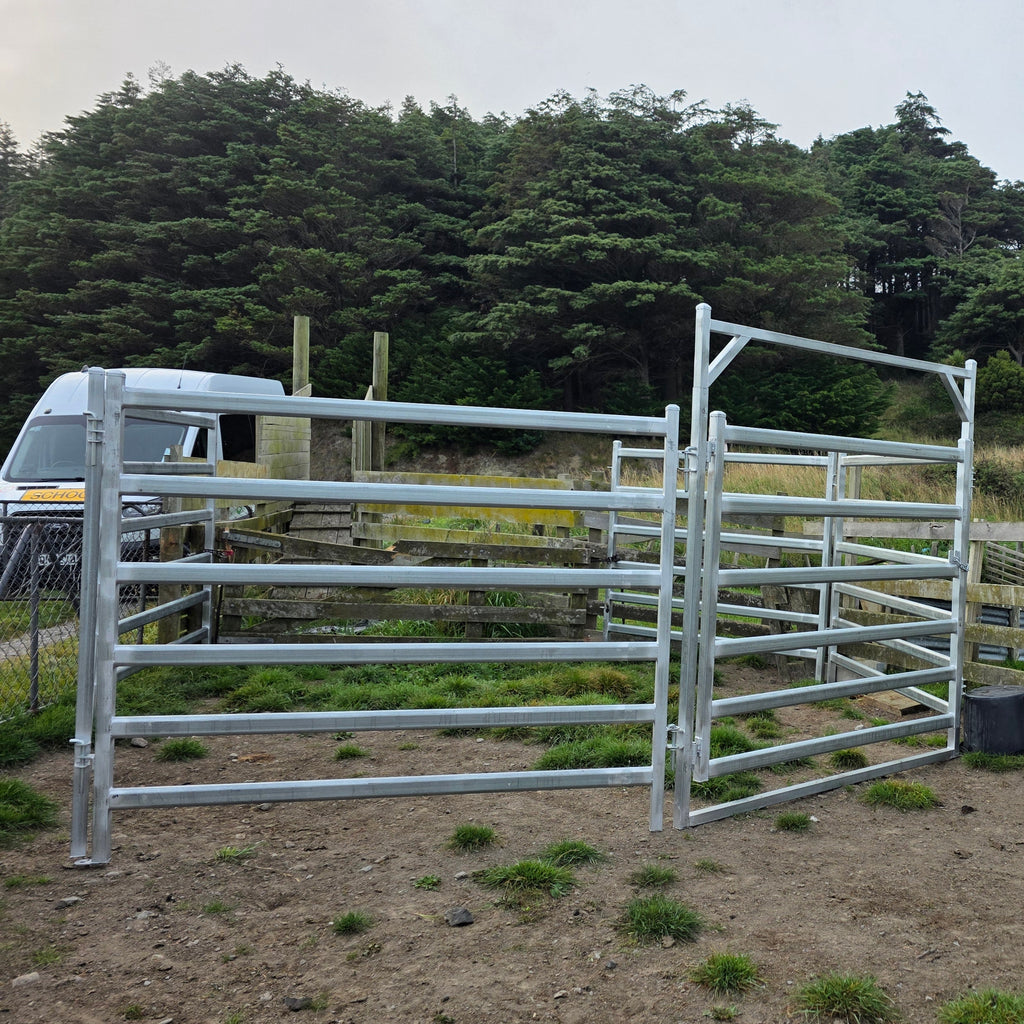 Assembled gate and panels on a gravel yard, with mature trees behind.