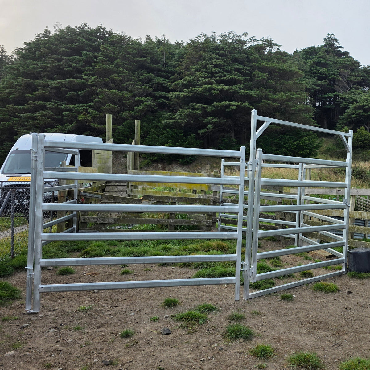 Assembled gate and panels on a gravel yard, with mature trees behind.