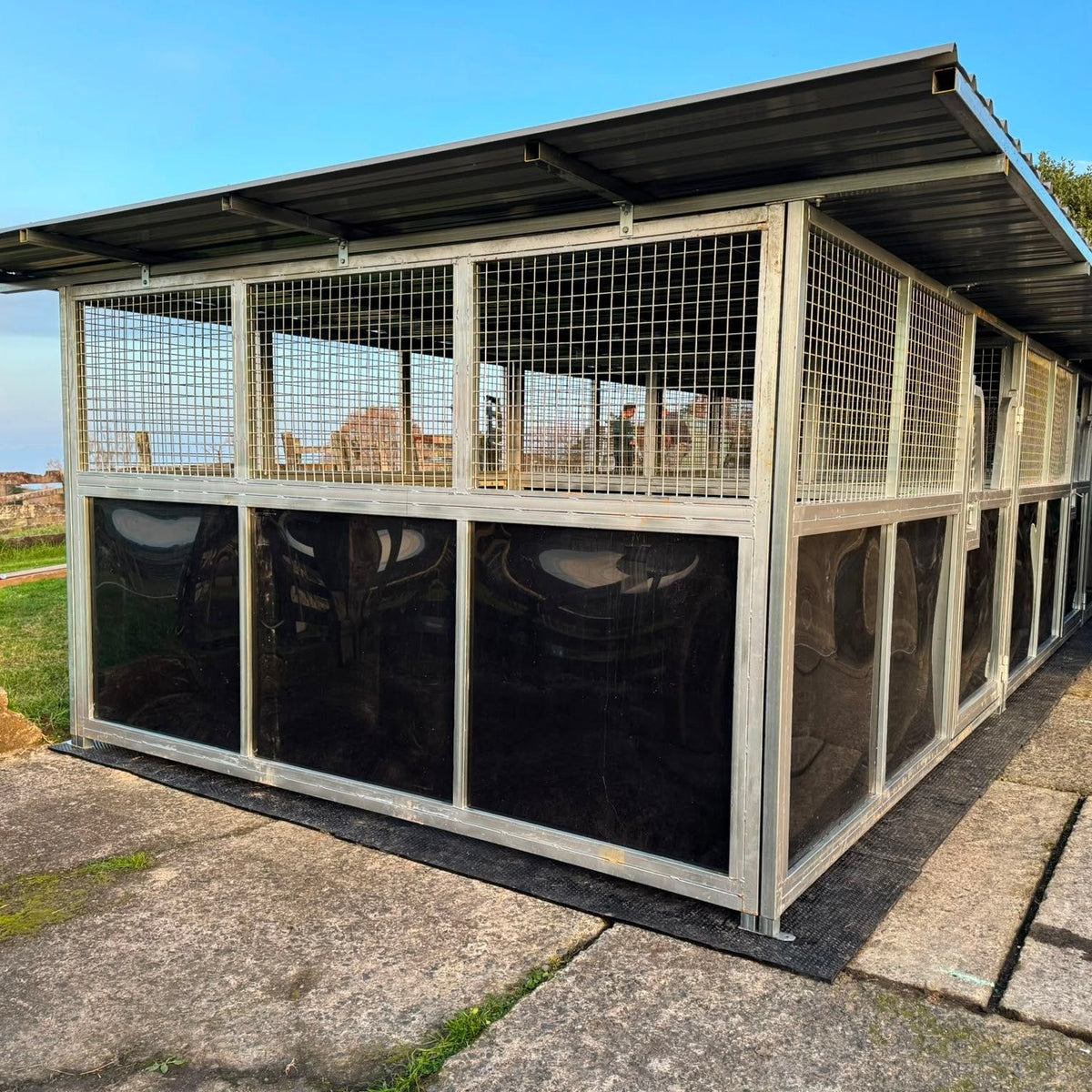 modular horse stable with roof and mesh panels installed on site, angled exterior view